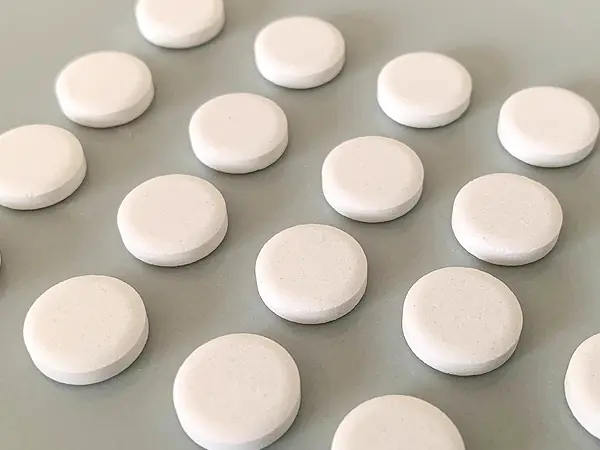 無印良品『歯みがきタブレット』の検証写真です。実物のタブレットの画像です。色は淡い白色で、大きさは1円玉より少し小さいぐらいのサイズです。