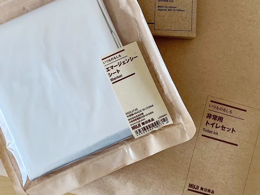無印良品『エマージェンシーシート』の検証写真です。シンプルな茶色のパッケージで、「いつものもしも」シリーズの「非常用トイレセット」とランダムに並べて撮影した画像です。視覚的に「いつものもしも」シリーズだということがわかります。