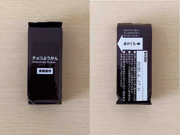 無印良品『備蓄おやつ チョコようかん』の検証写真です。5本入りの商品ですが、その中の1本単体の画像です。表裏ともに濃いブラウン色でチョコレートを連想される色合いです。表面には「チョコようかん 長期保存」と表示されおり、非常にシンプルなパッケージです。裏面には賞味期限と「あけくち」と表示されいて、その部分を引っ張れば開けれるようになっています。