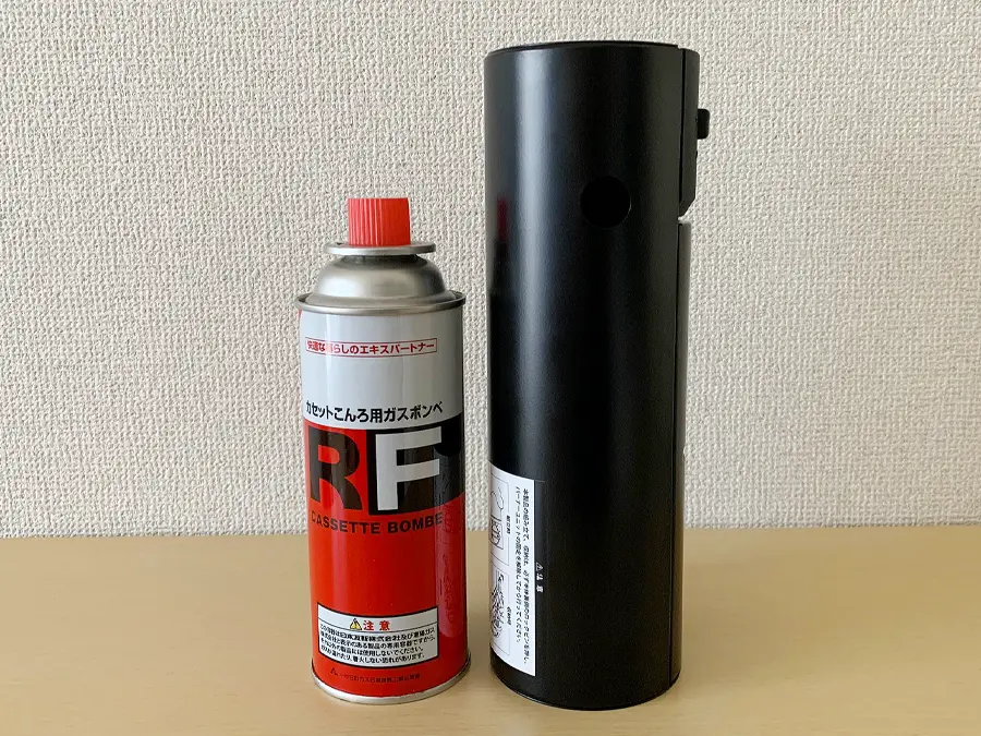 スノーピークから販売されている『Home & Campバーナー』の検証写真です。ガス缶と並べて、収納時にどれだけコンパクトになるかを説明した画像です。幅はガス缶とあまり変わらず、狭い空間にも収納することができそうです。